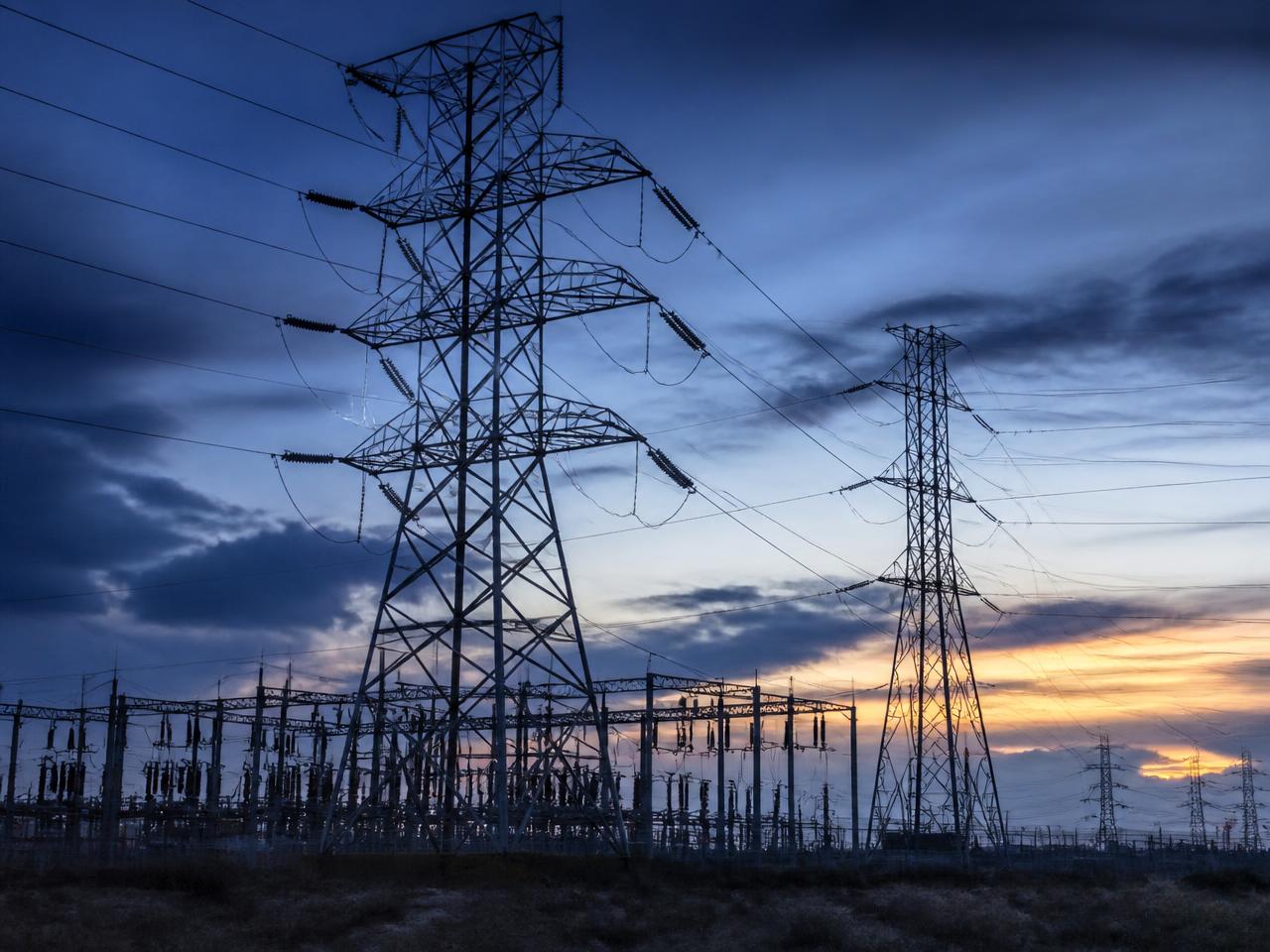 Torres de transmissão e subestação de energia elétrica ao anoitecer